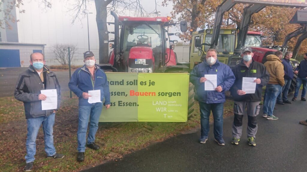 Landwirte mit dem Papier vor der DMK Deutsches Milchkontor in Neubörger